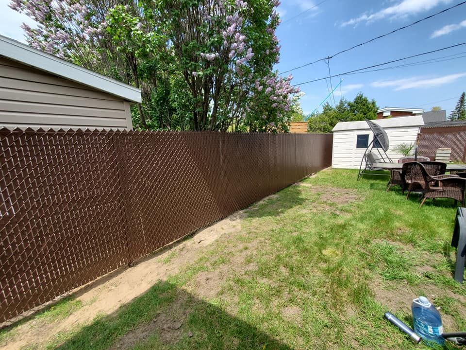 Une cour arriГЁre avec une clГґture Г  mailles losangГ©es et une table de pique-nique.