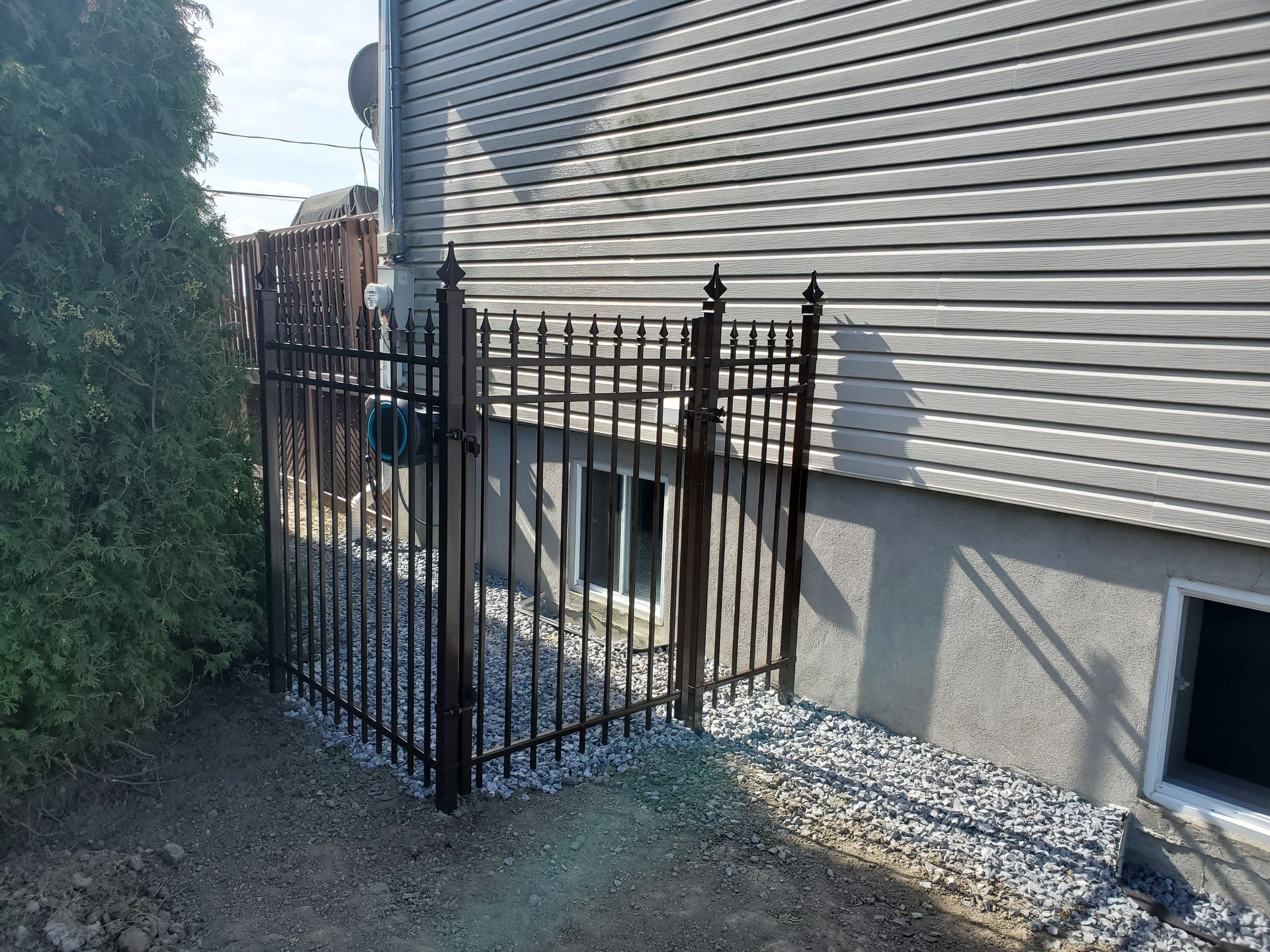 Une clГґture mГ©tallique entoure une fenГЄtre du sous-sol d'une maison.