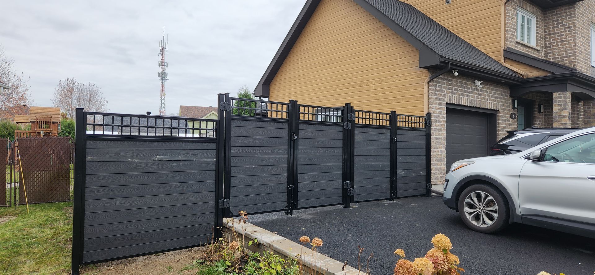 Une voiture est garГ©e devant une maison Г  cГґtГ© d'une clГґture.