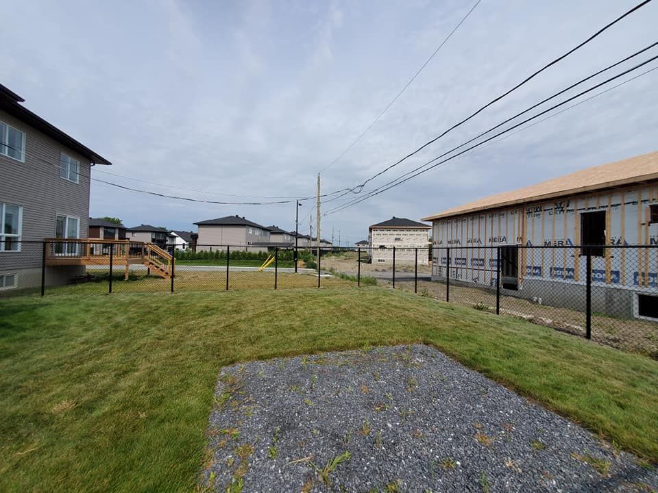 Une cour arriГЁre avec une clГґture et une maison en arriГЁre-plan.