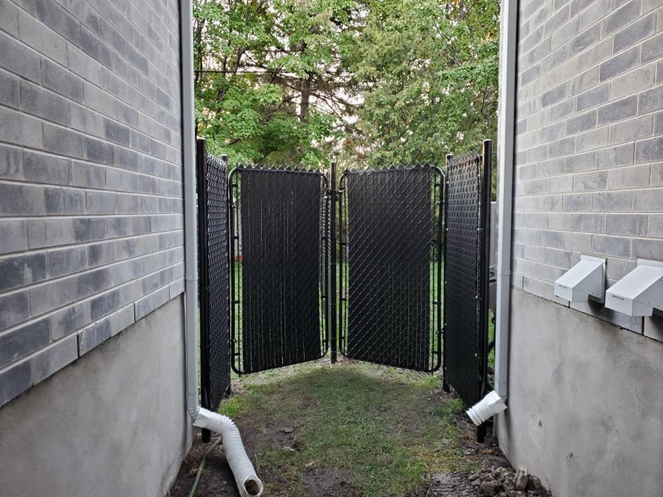 Une clГґture noire se trouve entre deux bГўtiments en briques.