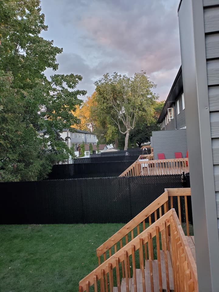 Une terrasse en bois avec des escaliers menant Г  une cour arriГЁre avec une clГґture noire.