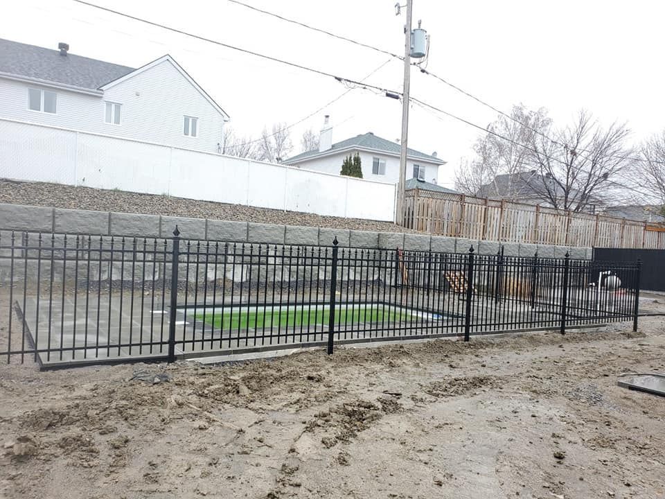 Une clГґture mГ©tallique entoure une piscine dans une cour arriГЁre