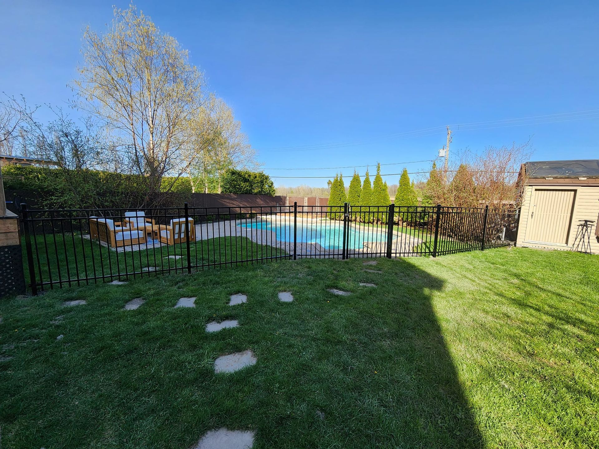 Une cour arriГЁre avec une clГґture et une piscine en arriГЁre-plan.