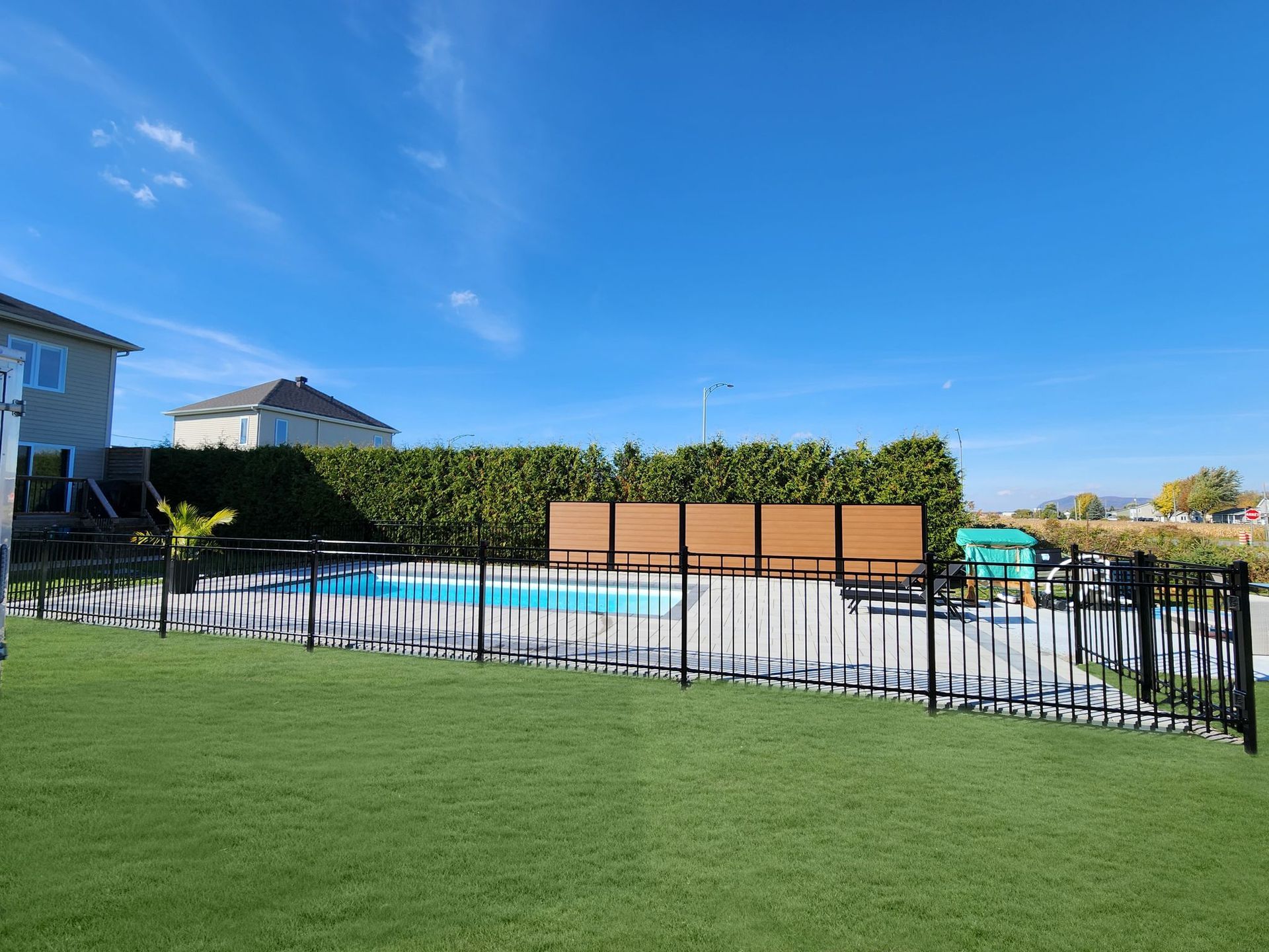 Une clГґture entoure une piscine dans une cour arriГЁre.