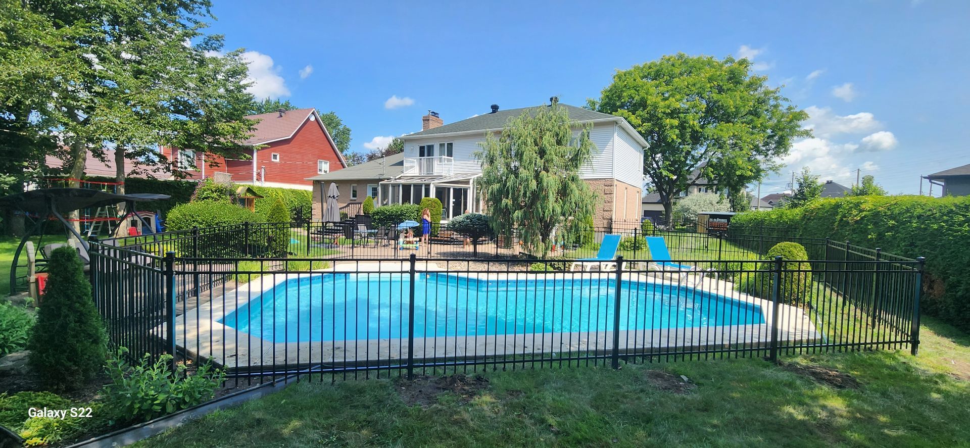 Une grande piscine entourГ©e d'une clГґture mГ©tallique dans une cour arriГЁre.