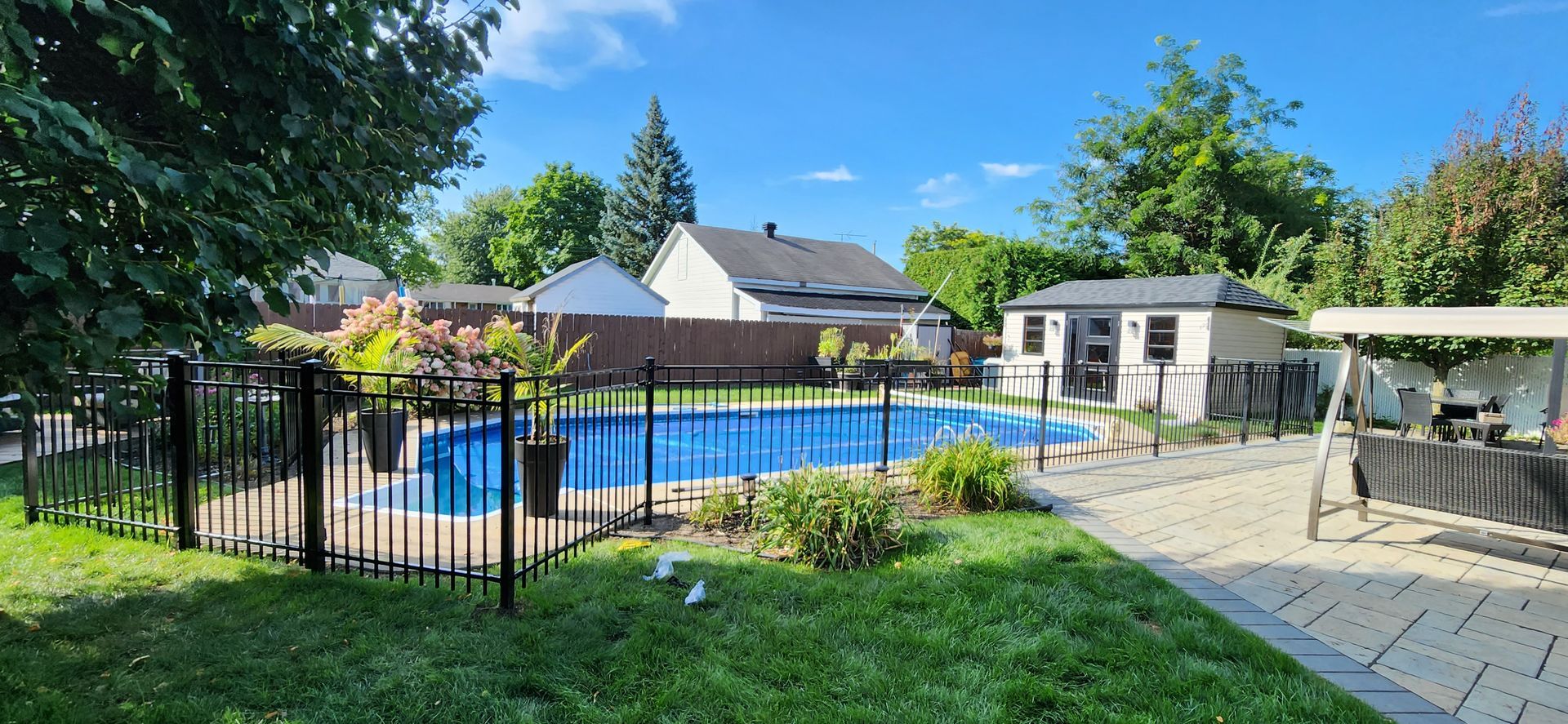Une grande piscine est entourГ©e d'une clГґture dans une cour arriГЁre.