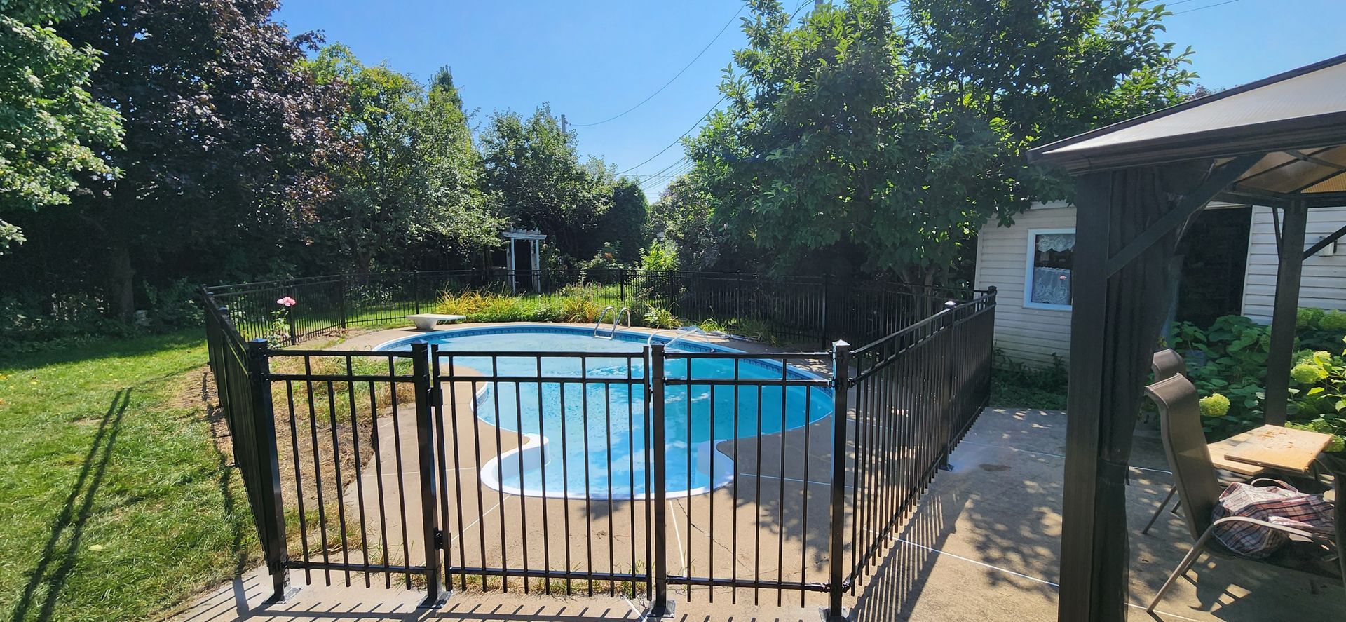 Une clГґture entoure une piscine dans une cour arriГЁre.