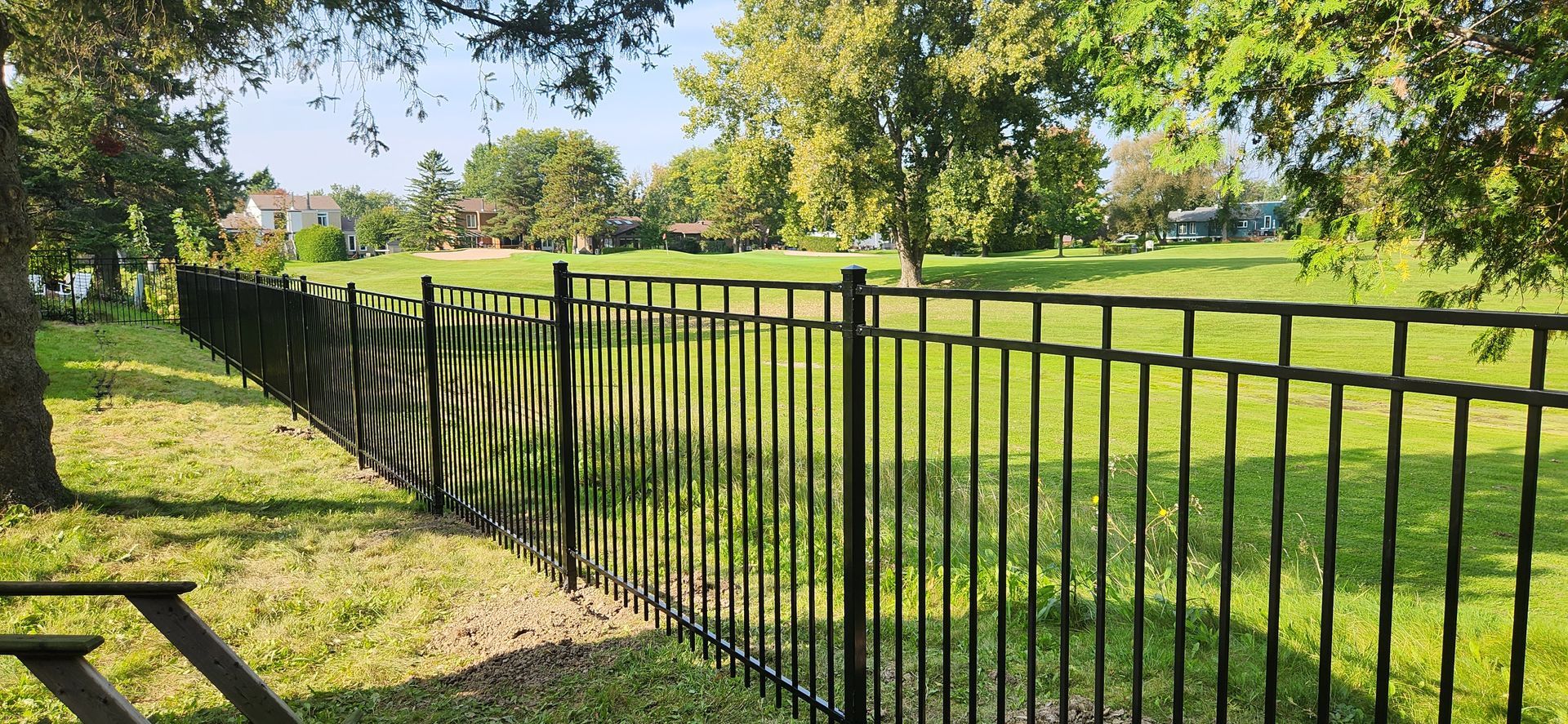 Une clГґture noire entoure une table de pique-nique dans un parc.