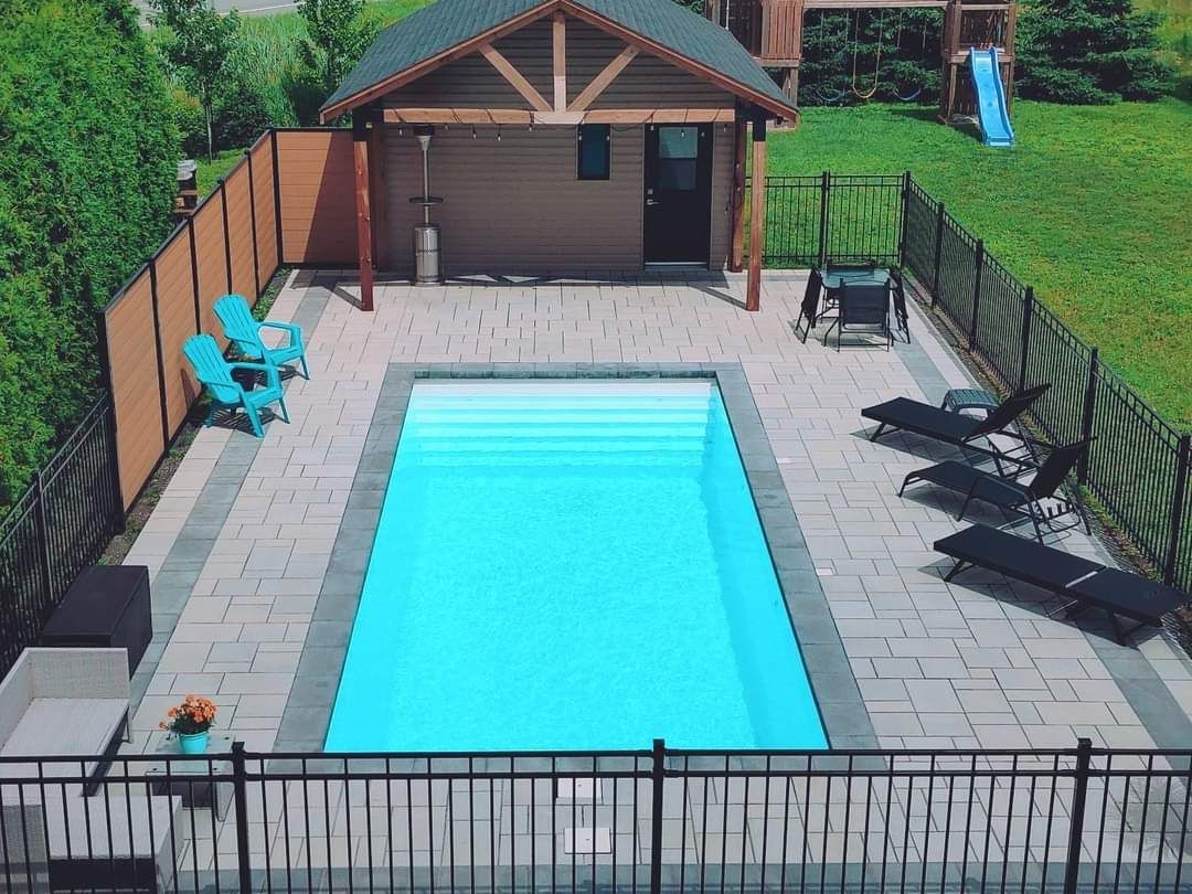 Une vue aГ©rienne d'une piscine entourГ©e de chaises et d'une clГґture