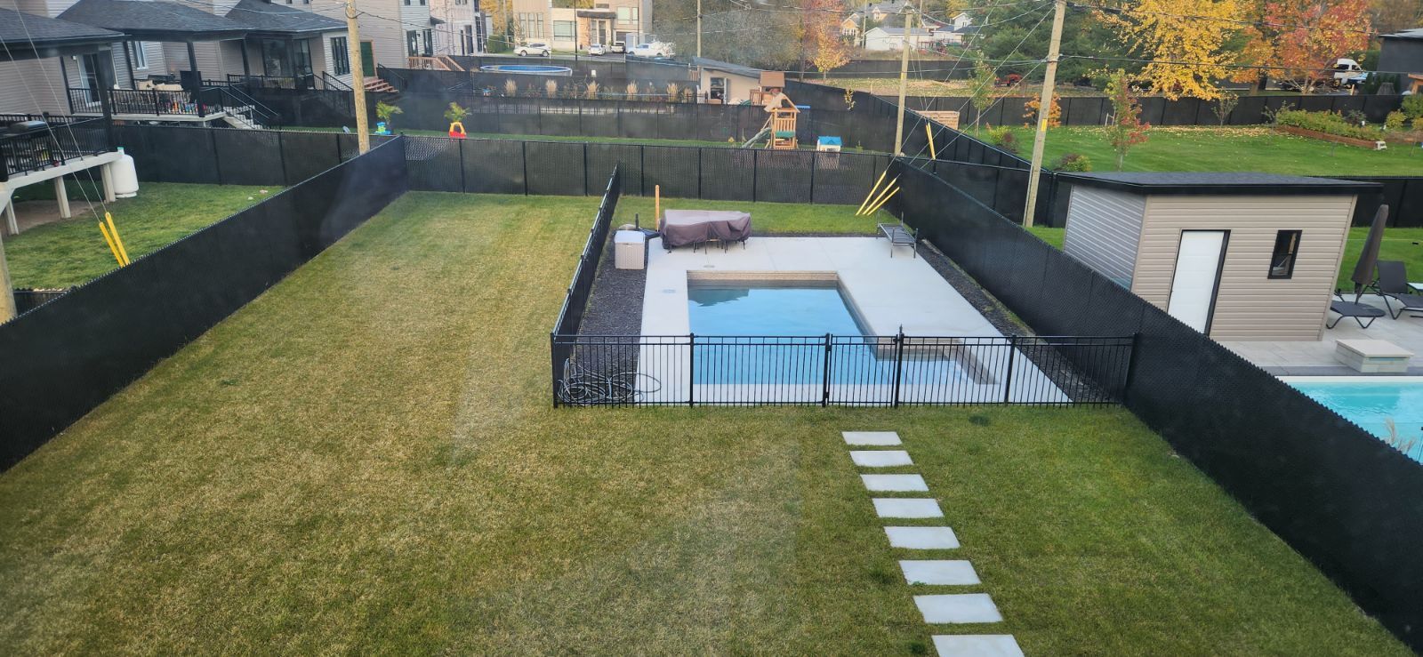 Une vue aГ©rienne d'une cour arriГЁre avec une clГґture et une piscine.