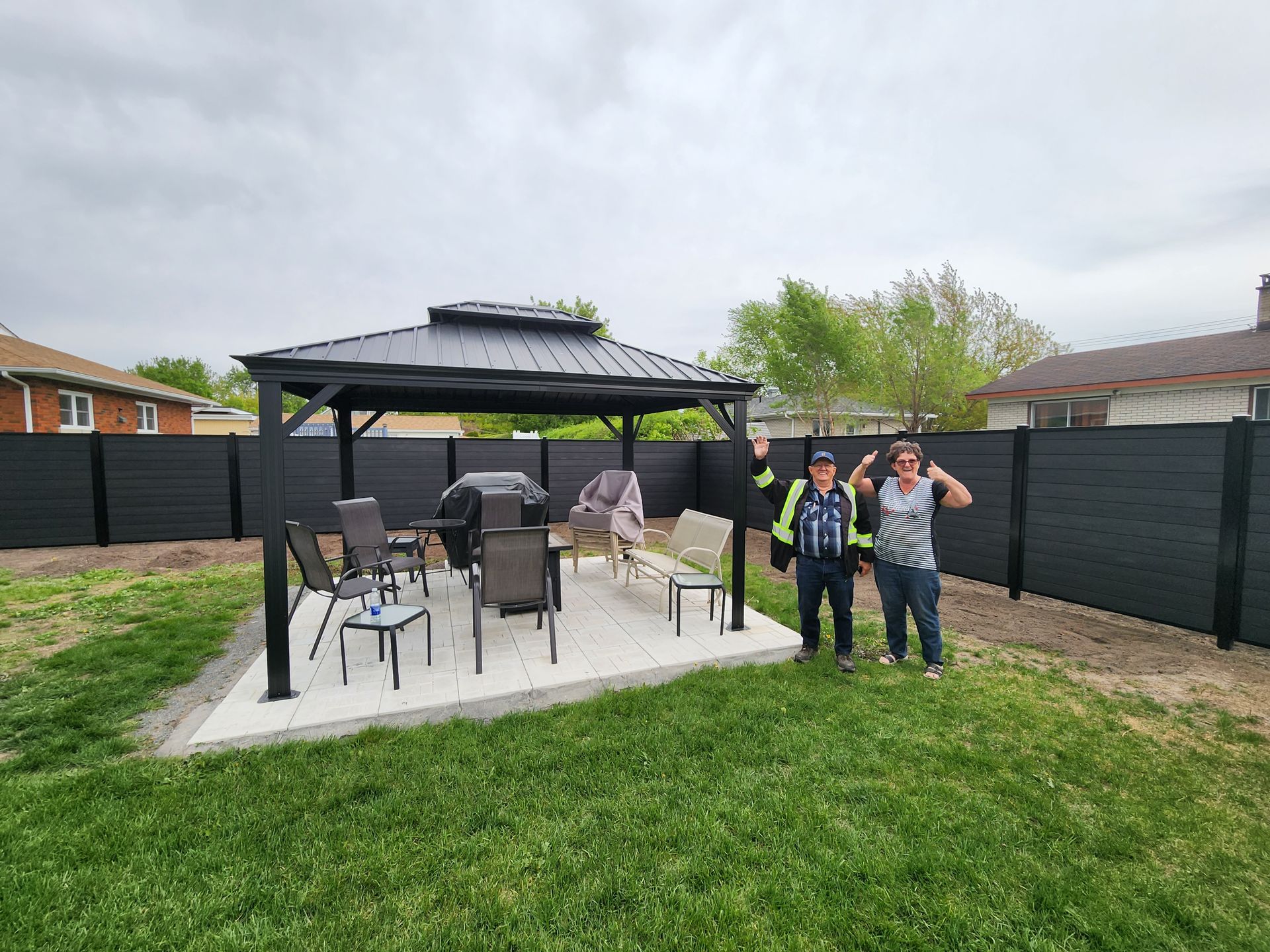 Deux hommes se tiennent devant un belvГ©dГЁre dans une cour arriГЁre.